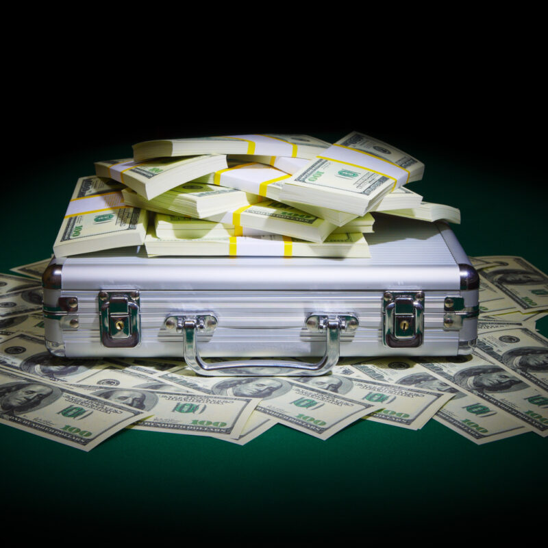 Metallic case with dollars on green table. Money that was seized by the government during forfeiture.