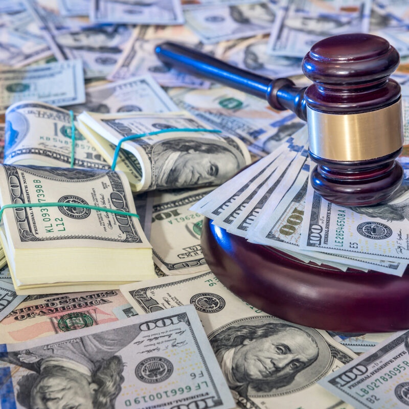 Auction concept - judges gavel against us dollar background indicating a financial crime.