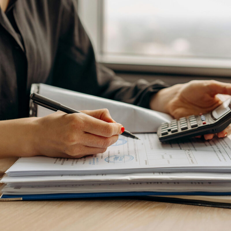 Close up of woman with pencil in one hand and calculator in the other
