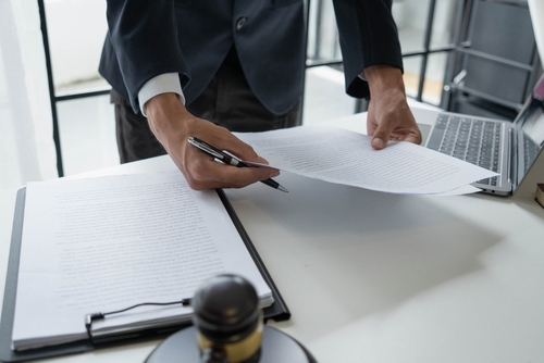 Lawyers reviewing contract documents beside brass scales of justice during office meeting