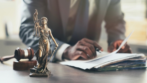 Scale of justice beside law books and gavel on courtroom desk