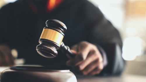 judge in robes striking wooden gavel on sound block in courtroom
