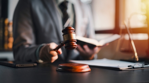attorney holding gavel and open book at desk with legal documents